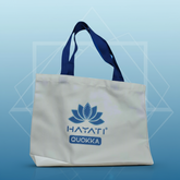 White tote bag with blue handles and 'HATATI QUOKKA' logo on a light background